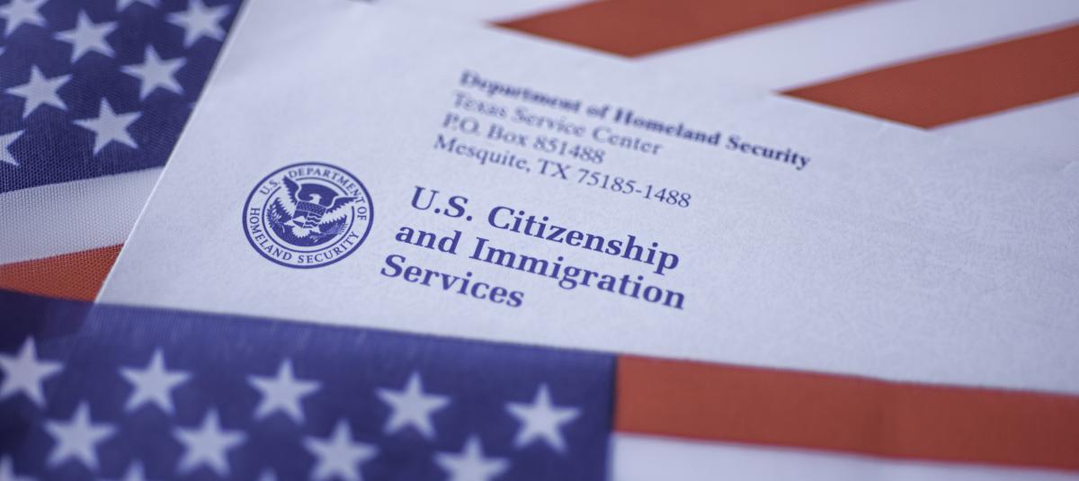 U.S. Citizenship and Immigration Services letter on top of an American flag background.