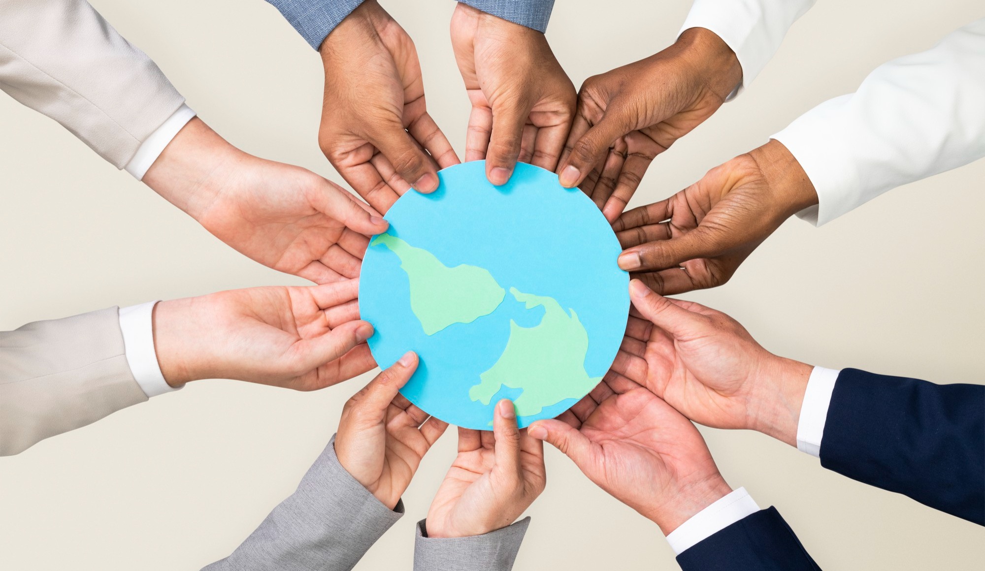 127168 Diverse hands holding a paper cutout of the Earth, symbolizing unity and global cooperation.