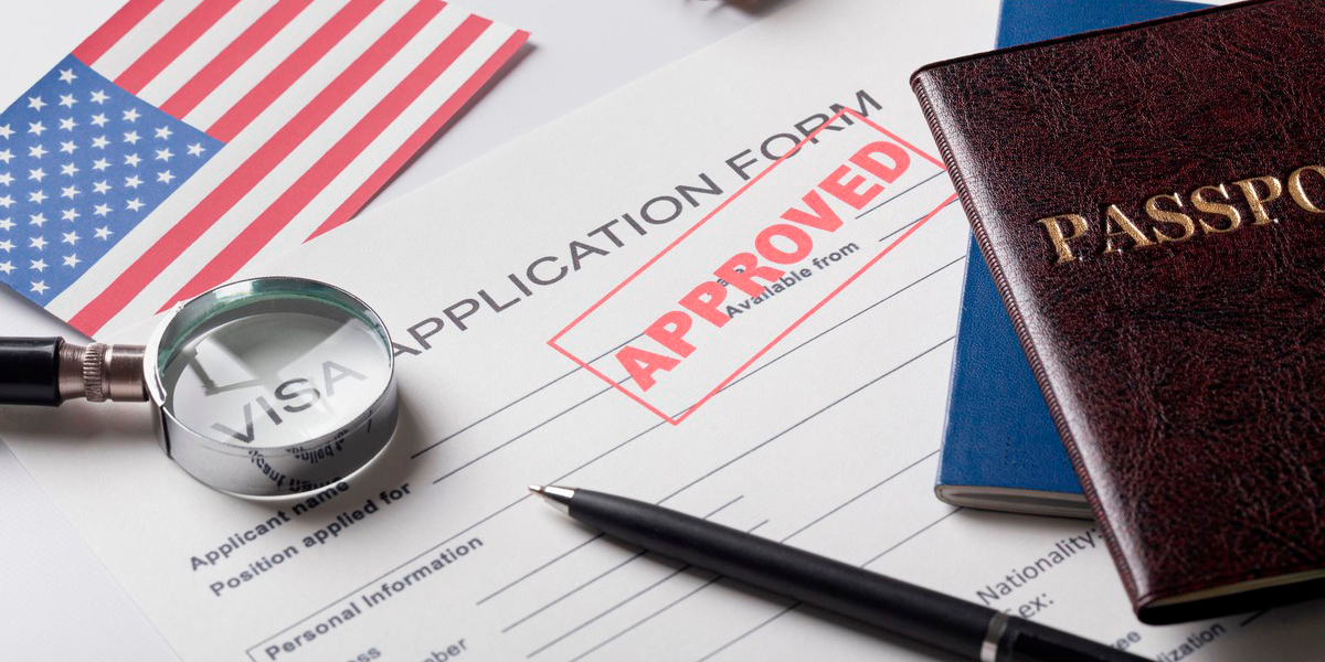 Visa application form stamped "APPROVED" with a passport, pen, magnifying glass, and a small US flag.