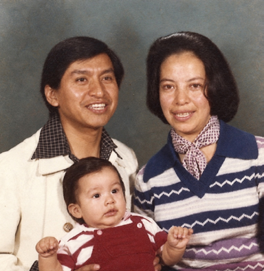A man, a woman, and a baby posing for a family portrait.