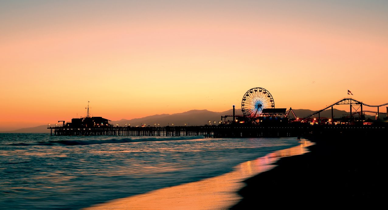 Santa Monica Pier with a lit-up Ferris wheel at sunset.